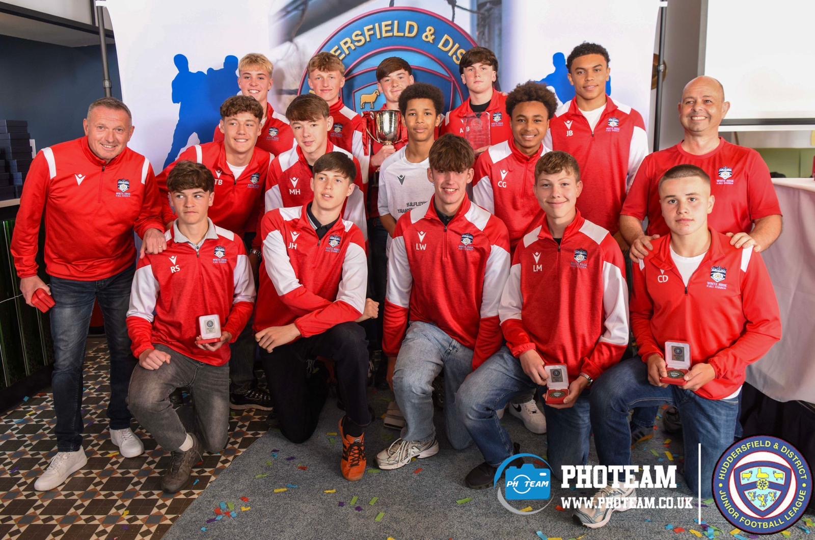 White Rose players and coaches in club tracksuits with medals and a cup