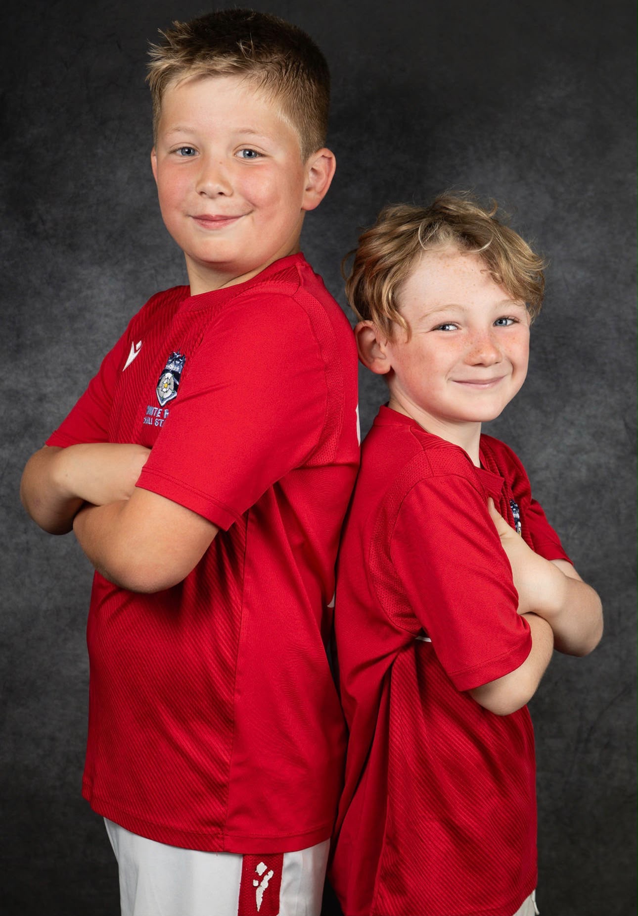 Two players back to back with arms folded in red shirts